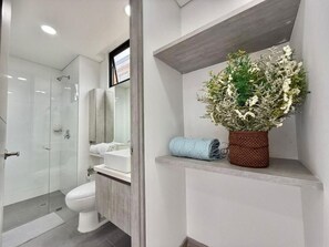 Une salle de bain moderne avec une douche à parois de verre, des toilettes blanches et un meuble-lavabo en bois.