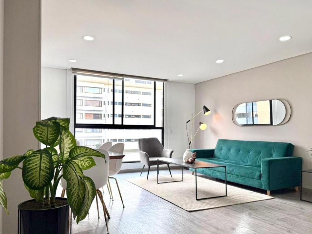 Uma sala de estar moderna com sofá, cadeiras, mesa de centro, planta em vaso e uma janela grande.