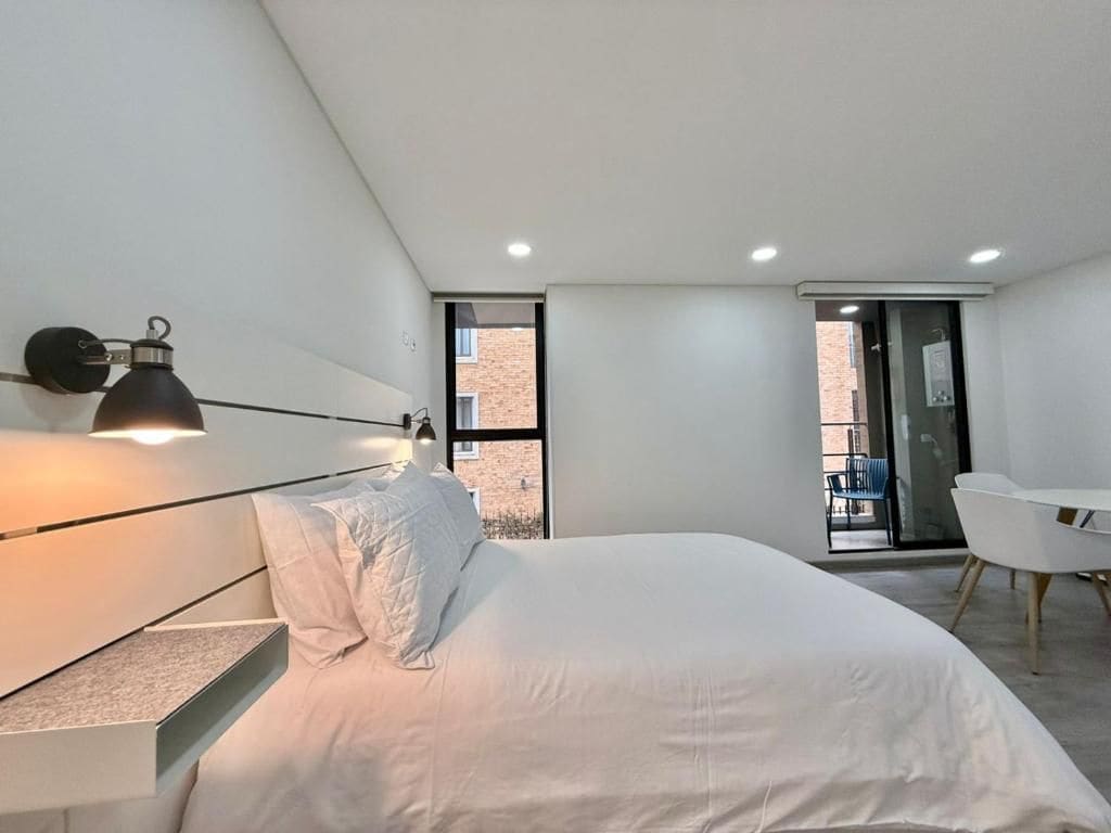 Un dormitorio moderno con cama, mesita de noche y una silla.