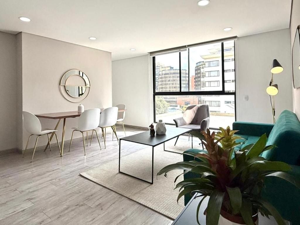 Una sala de estar moderna con comedor, ventanas amplias y vistas a edificios.