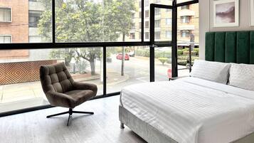 Une chambre d’hôtel avec une grande fenêtre, un lit, une chaise et une vue sur la rue.