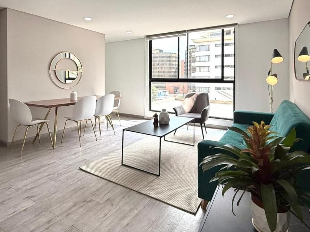 A modern living room with a sofa, a coffee table, and a dining area with chairs.