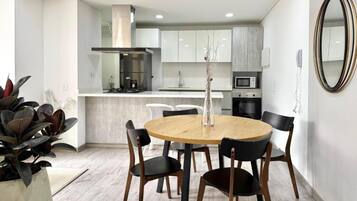 Una cocina moderna con armarios blancos, una isla central y un comedor con una mesa redonda y sillas.
