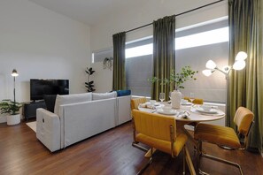 En moderne stue med sofa, spisebord til to og et fjernsyn.