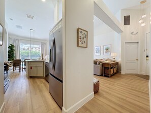 A modern kitchen with a large refrigerator, wooden flooring, and a dining area with a table and chairs. - Sundrop Oasis ☀️ | Remodeled 3-Bedroom Private Pool Villa Near Disney (Davenport)