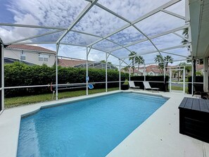 Piscina coberta com espreguiçadeiras e vista para edifícios residenciais.