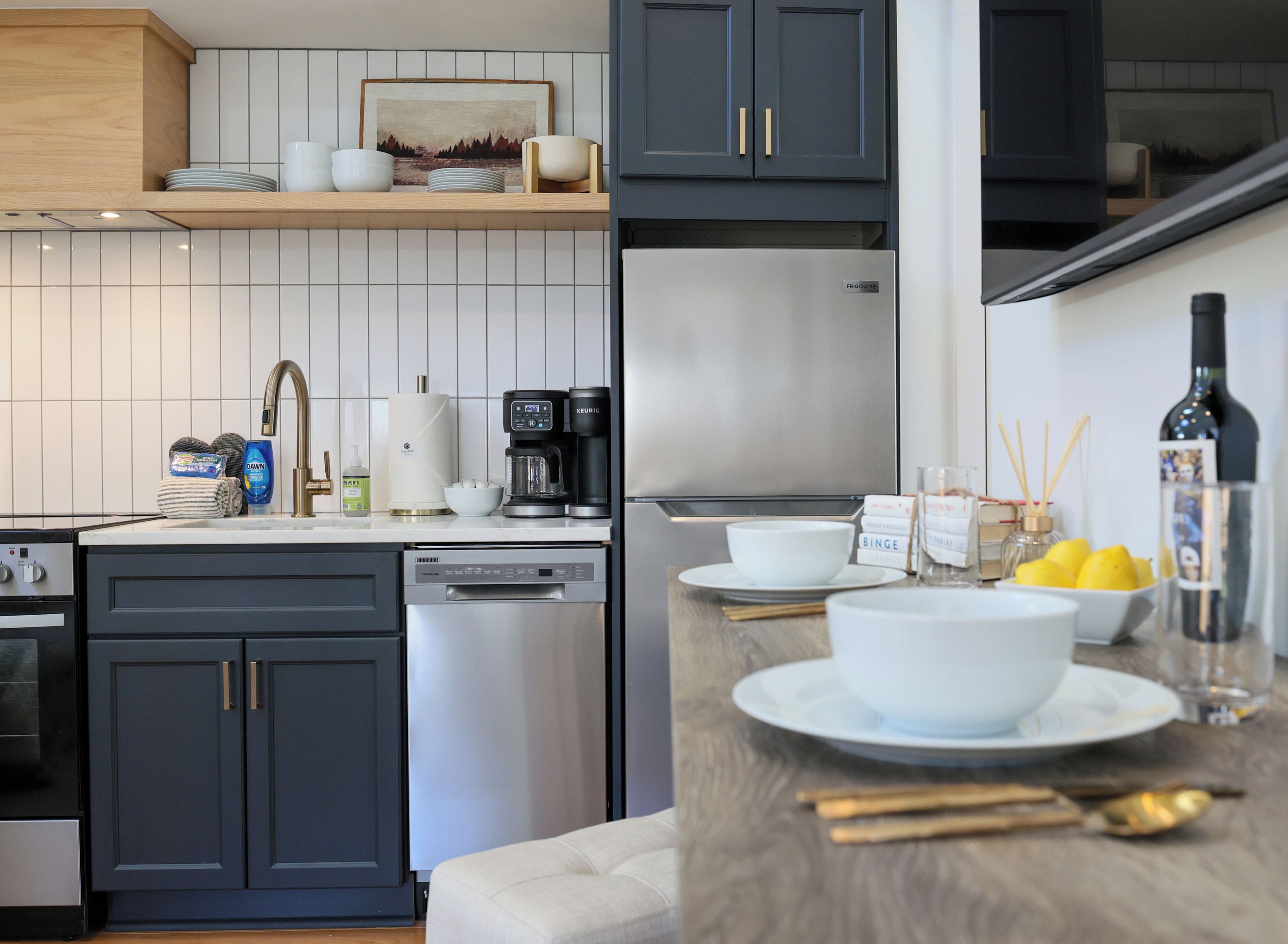 A modern kitchen with a dishwasher, coffee maker, and a wine bottle on the counter.
