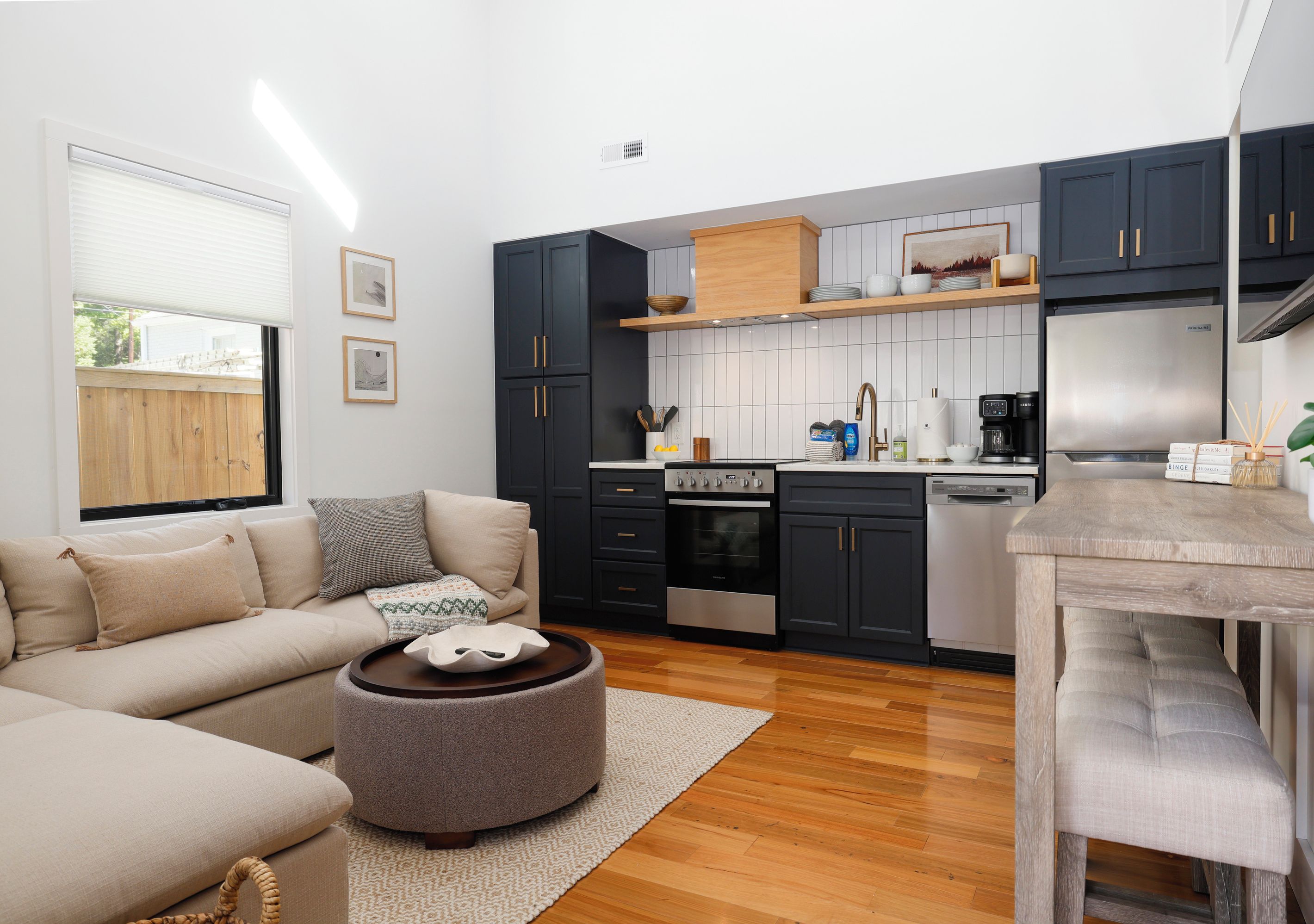 A modern kitchen with dark cabinets, a built-in oven, and a coffee machine.