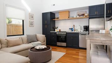 A modern kitchen with dark cabinets, a built-in oven, and a coffee machine.