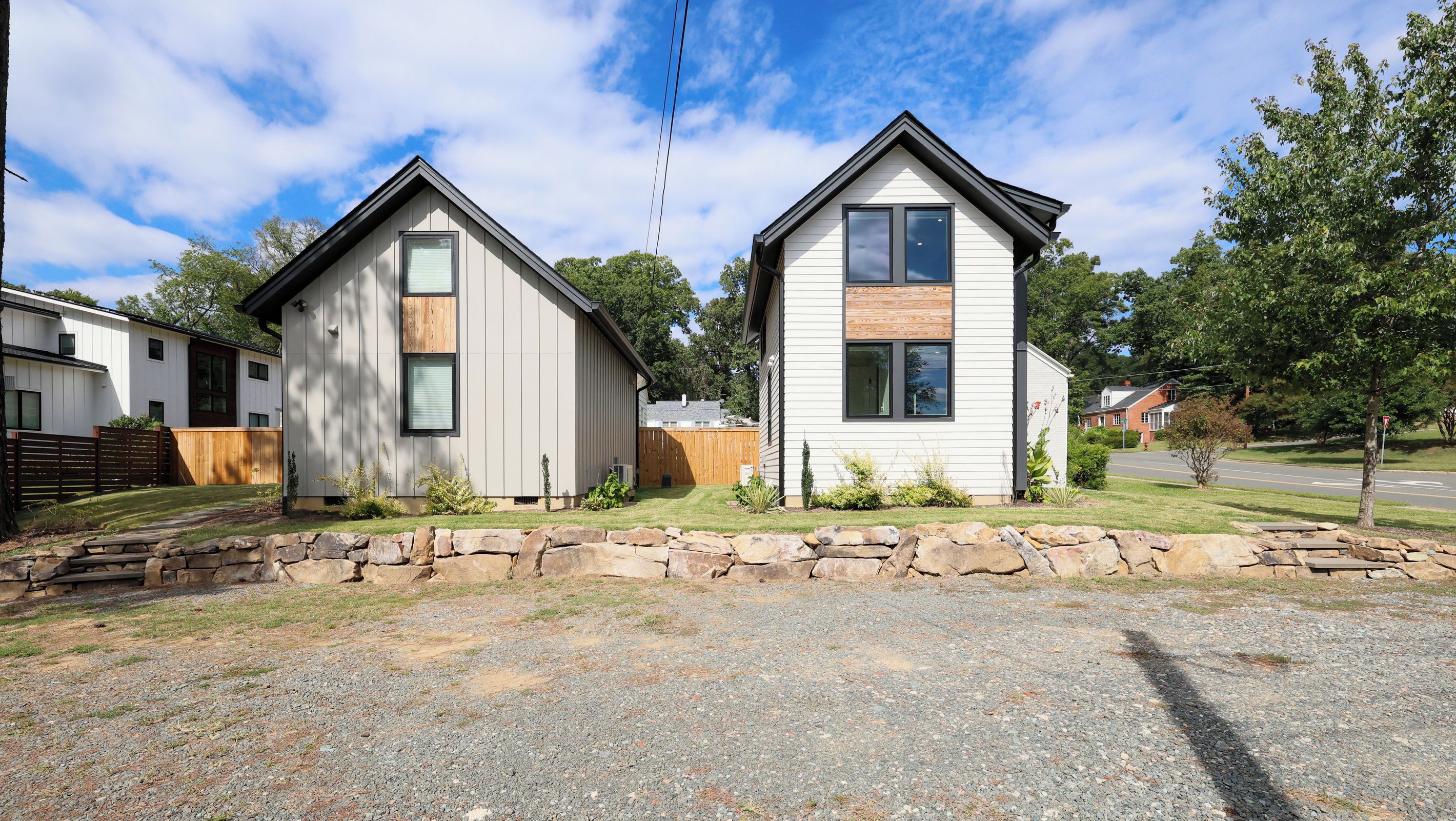 A residential property with two detached houses, a stone wall, and a gravel driveway.