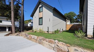 A modern two-story house with a stone retaining wall, a well-maintained lawn, and a clear blue sky.