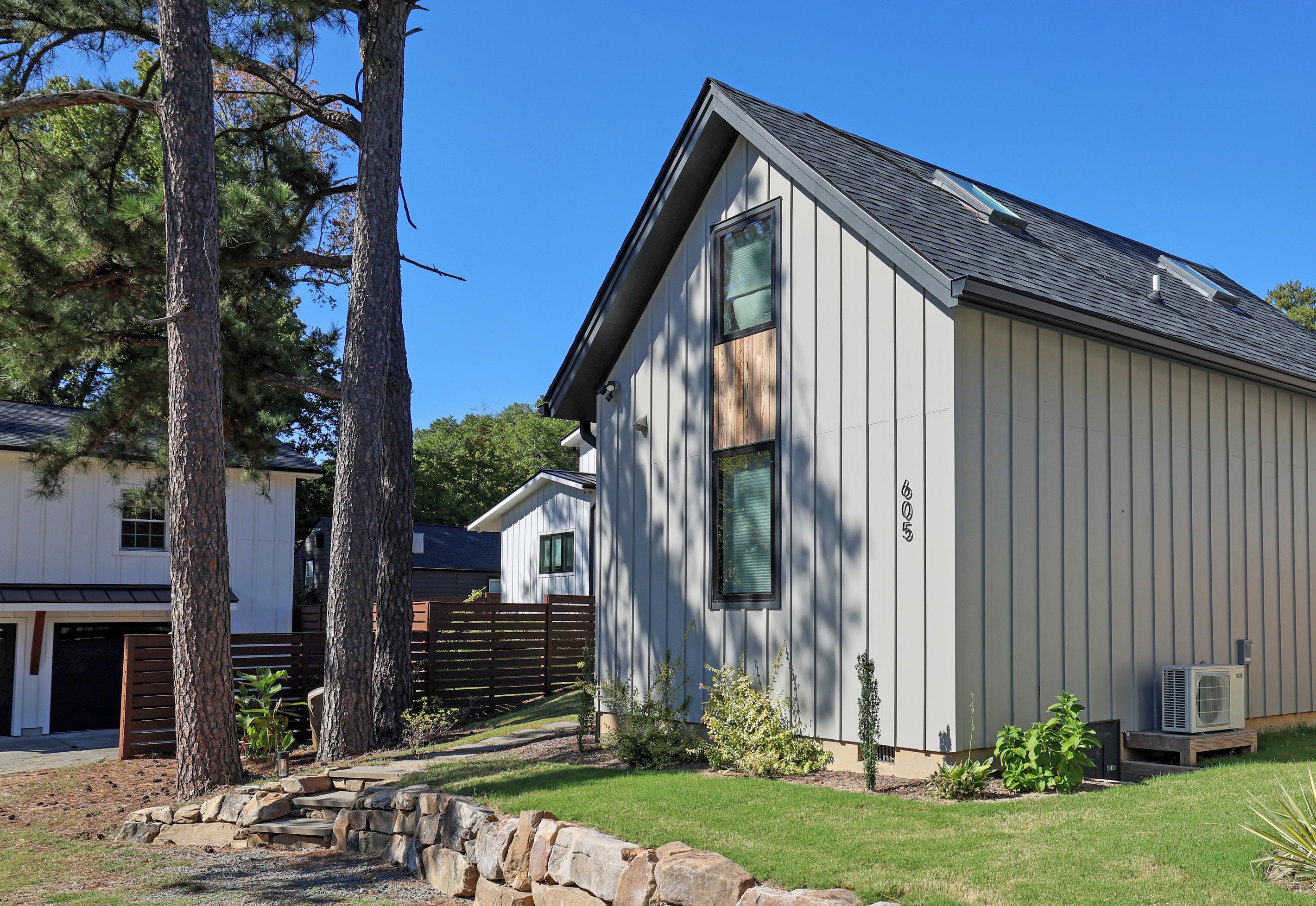 A residential building with a sloped roof, a garage, and a stone retaining wall.