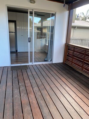 A wooden deck with a sliding glass door leading to a kitchen area.