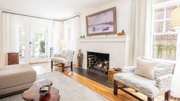 A living room with a fireplace, a zebra-striped sofa, a wooden coffee table, and a painting above the fireplace.