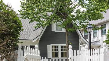 A residential property with a white picket fence, a stone staircase leading to a front door, and a house with a dark siding exterior.