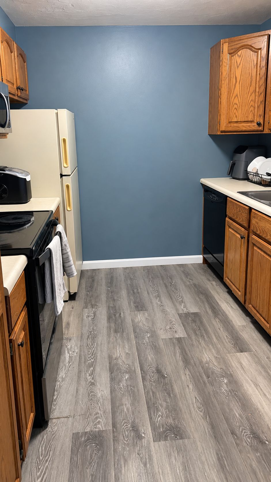 A kitchen with wooden cabinets, a refrigerator, a stove, and a dishwasher.