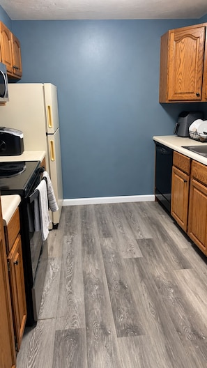 A kitchen with wooden cabinets, a refrigerator, a stove, and a dishwasher. - Cozy & Stylish 2-bedroom 1.5 bath townhouse in central MAss Home Getaway. (Leominster)