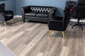 A room with a tufted leather sofa, two black armchairs with gold legs, and a printer on a small table. - Cozy & Stylish 2-bedroom 1.5 bath townhouse in central MAss Home Getaway. (Leominster)