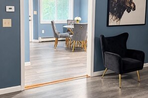 A modern interior with a dining area, a black chair, and a wall-mounted artwork.