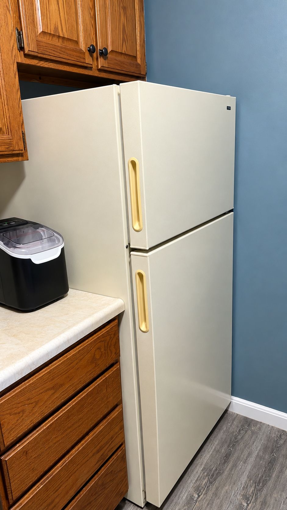 A kitchen with a white refrigerator, wooden cabinets, and a countertop.