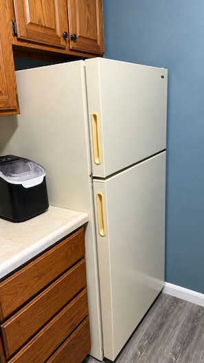 A kitchen with a white refrigerator, wooden cabinets, and a countertop.