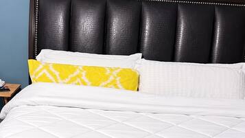 A bed with a dark headboard, white bedding, and a grey blanket.