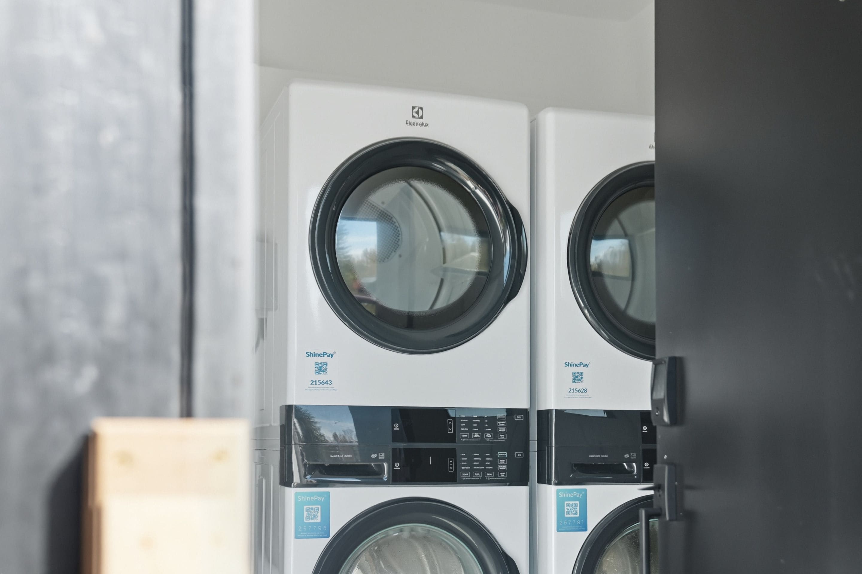 A row of front-loading washing machines with a control panel and a QR code for payment.