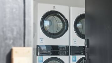 A row of front-loading washing machines with a control panel and a QR code for payment.