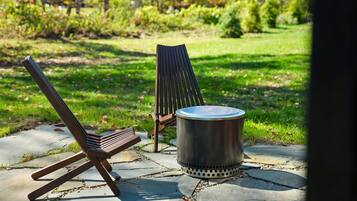 A patio with two chairs and a metal trash can.