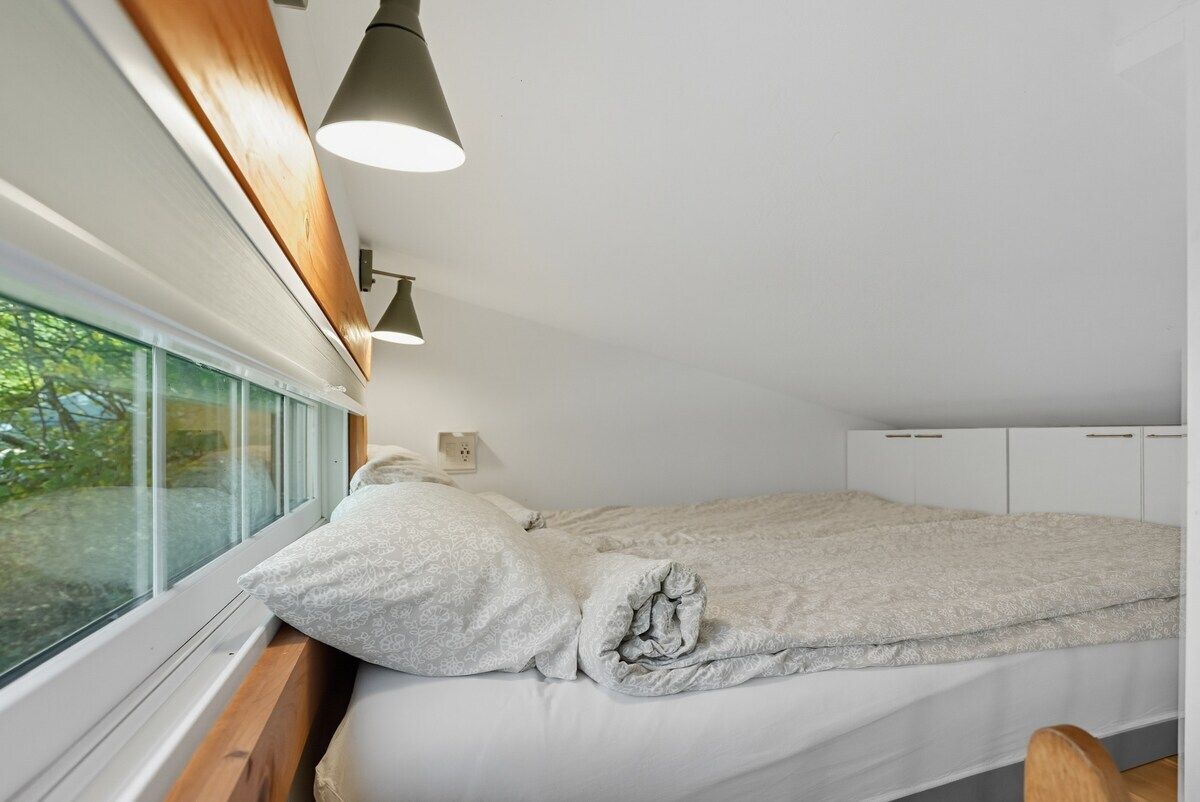 A bedroom with a bed, a window, and a wooden headboard.
