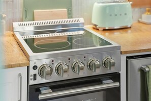 Una cocina con estufa y horno integrados, un tostador y una encimera de madera.