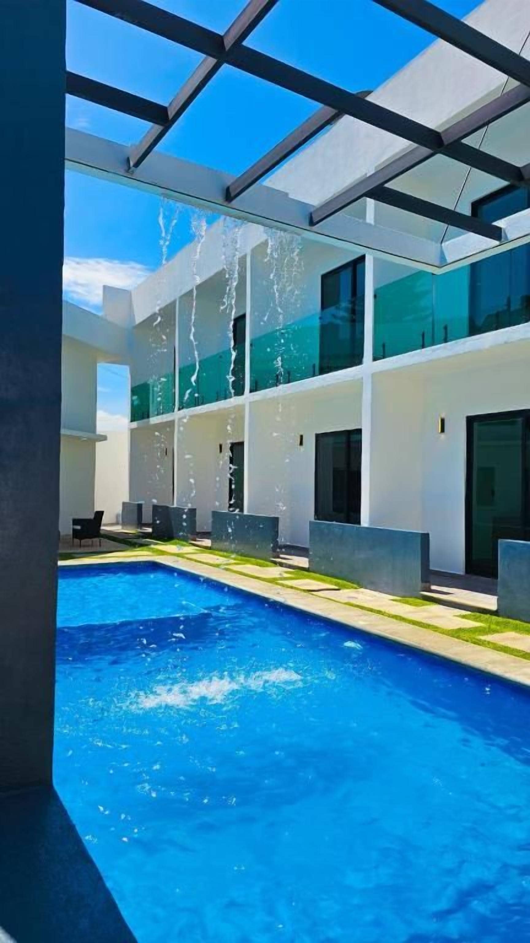 Un edificio moderno con piscina, ventanas amplias y cielo despejado.