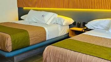 Habitación de hotel con dos camas, un cabecero de madera y una mesita de noche con una lámpara.