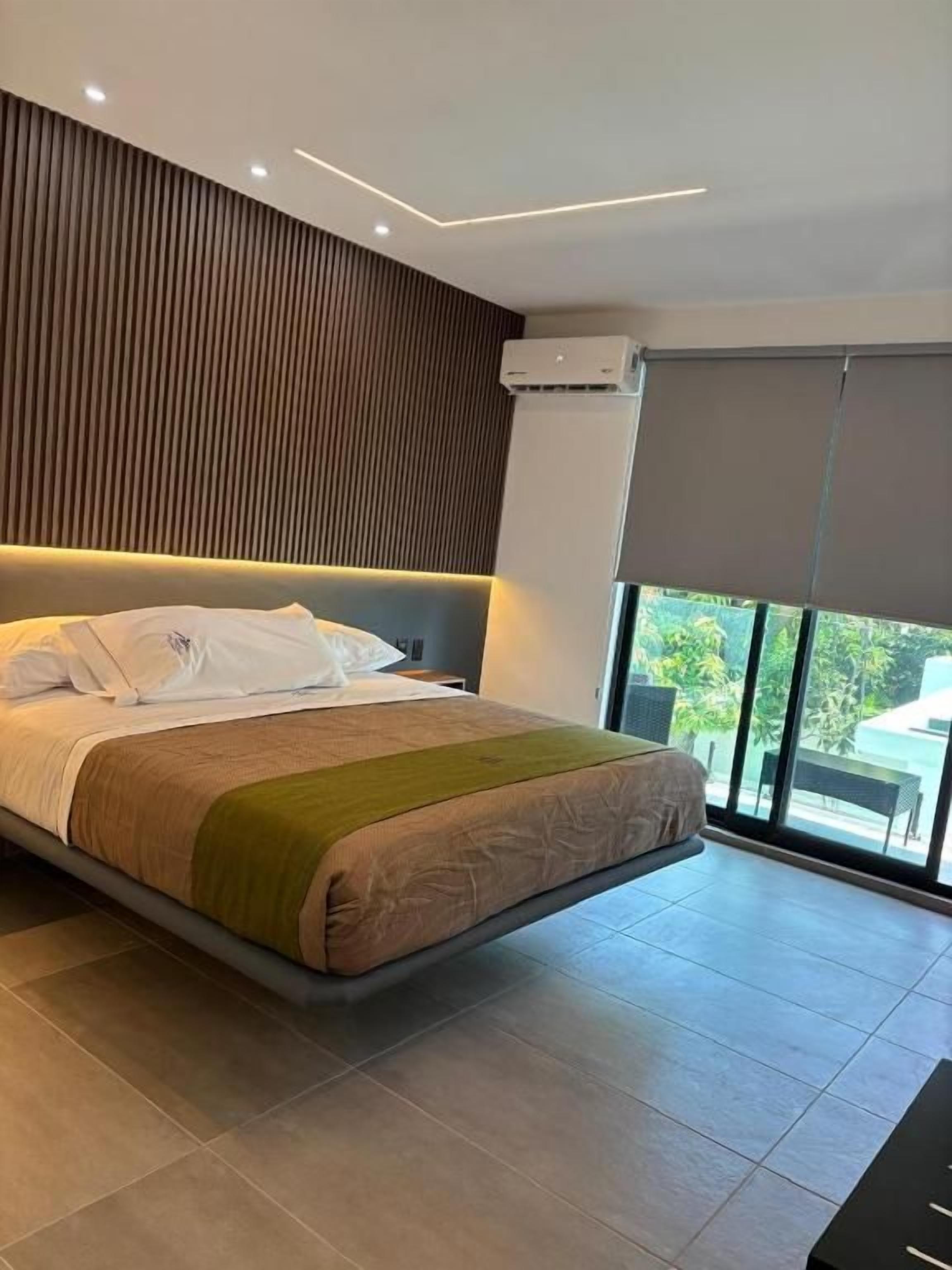 A modern bedroom with a large bed, a sloped ceiling, and a view of the outdoors.