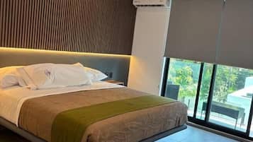 A modern bedroom with a large bed, a sloped ceiling, and a view of the outdoors.
