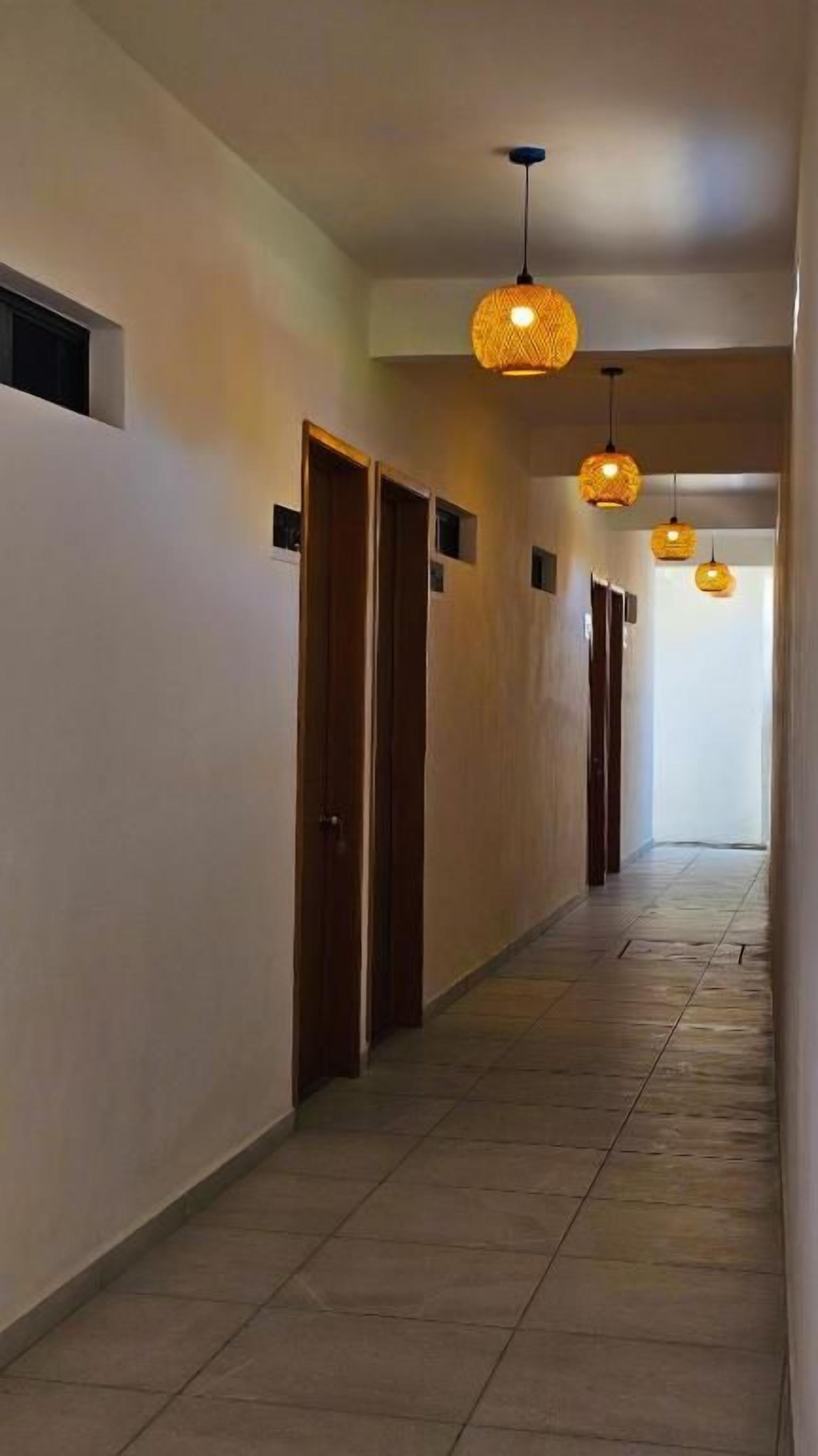 Passadís amb portes, lluminàries penjants i paviment de rajoles.
