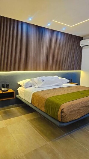 A modern hotel room with a large bed, a wooden headboard, and a nightstand. - Hotel San Carlos Boutique (YAUTEPEC DE ZARAGOZA)