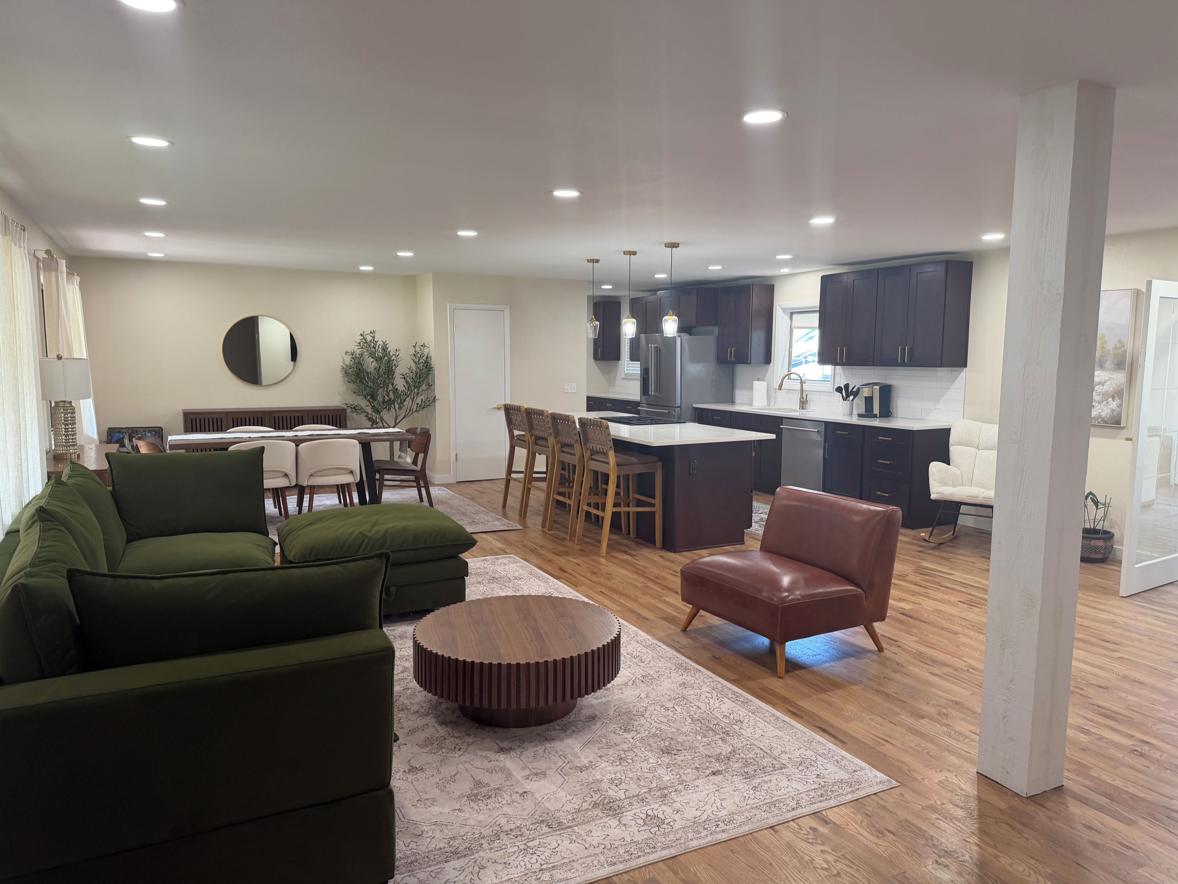 A modern living room with a sofa, a coffee table, and a dining area with chairs and a table.
