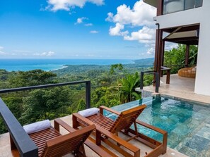 A poolside area with wooden loungers and a view of a lush landscape. - Octagon Villa by Pura Villas (Bahía Ballena)