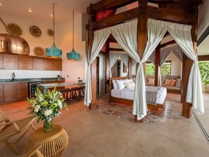 A bedroom with a canopy bed, a sitting area with a table and chairs, and a kitchen area with a dining table. - Octagon Villa by Pura Villas (Bahía Ballena)