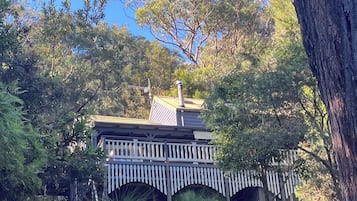 A building with a balcony and a chimney, surrounded by trees and vegetation.