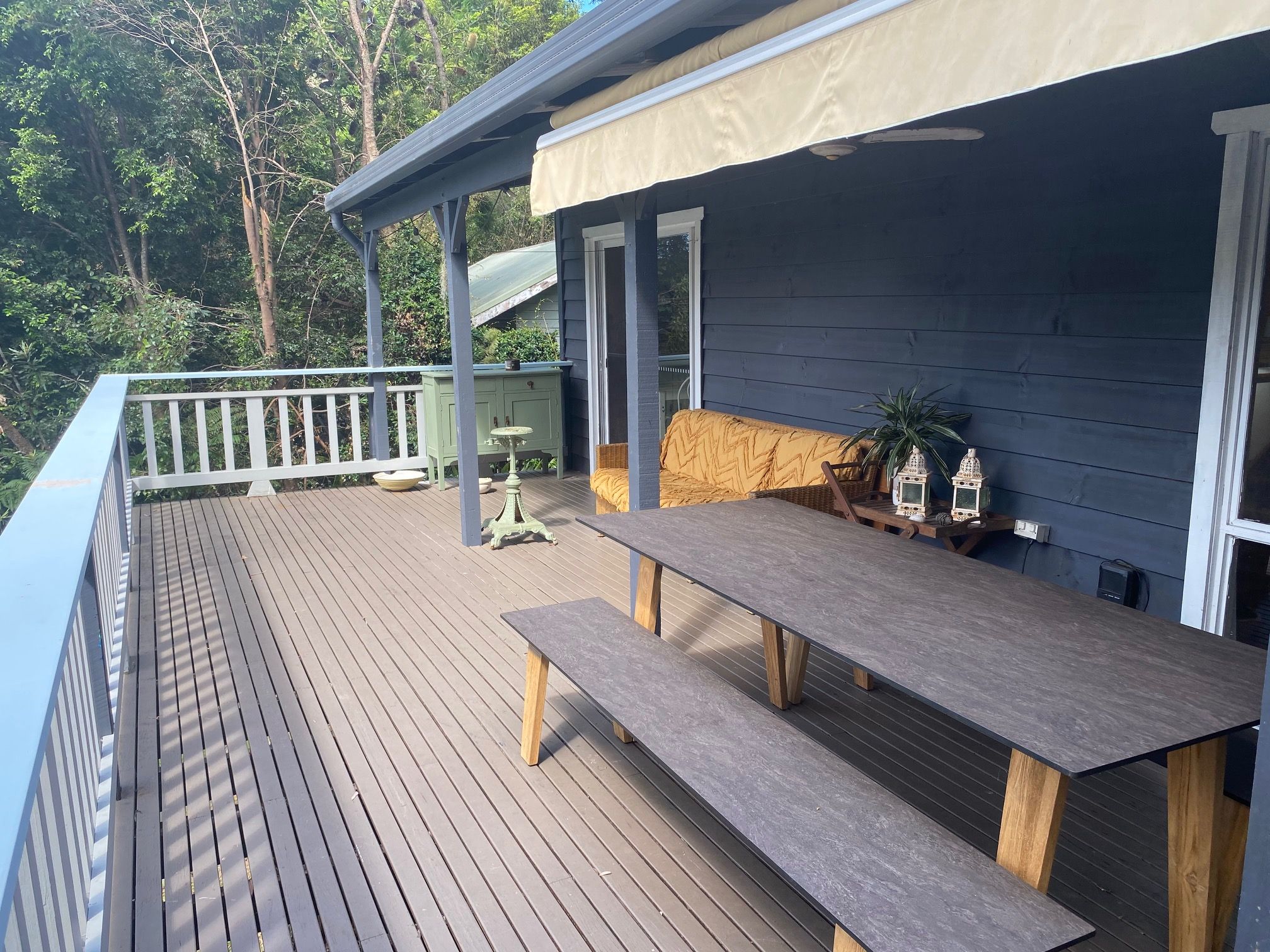 Una terraza de madera con bancos y una mesa, con vistas a un área boscosa.