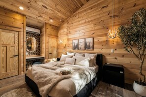 A wooden interior with a bed, a wall-mounted heater, and a potted plant. - Romantic Smoky Mountain Hideaway | Waterfront (Sevierville)