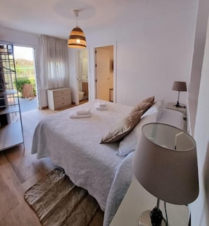 Ein Schlafzimmer mit Bett, Nachttischlampe und Blick ins Freie.