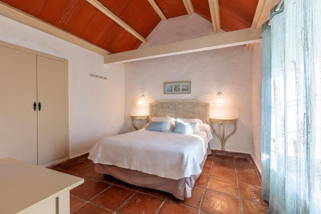 A bedroom with a bed, two bedside lamps, a wardrobe, and a small table.