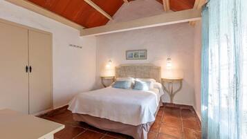 A bedroom with a bed, two bedside lamps, a wardrobe, and a small table.