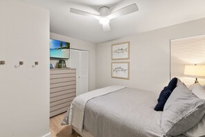A bedroom with a bed, a ceiling fan, a TV, and framed artwork on the wall. - 3BR Canal-Front Condo l Dock & Community Pool (Marco Island)