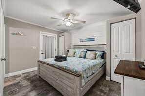 Un dormitorio con una cama, ventilador de techo y piso de madera.
