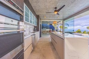 Una cocina moderna con horno empotrado, electrodomésticos de acero inoxidable y vistas al océano.