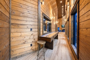 A wooden interior with a bar area, a stool, and a television mounted on the wall. - Broken Bow Bliss · Private Heated Pool, Hot Tub & Arcade Game Room | Sleeps 12 (Broken Bow)
